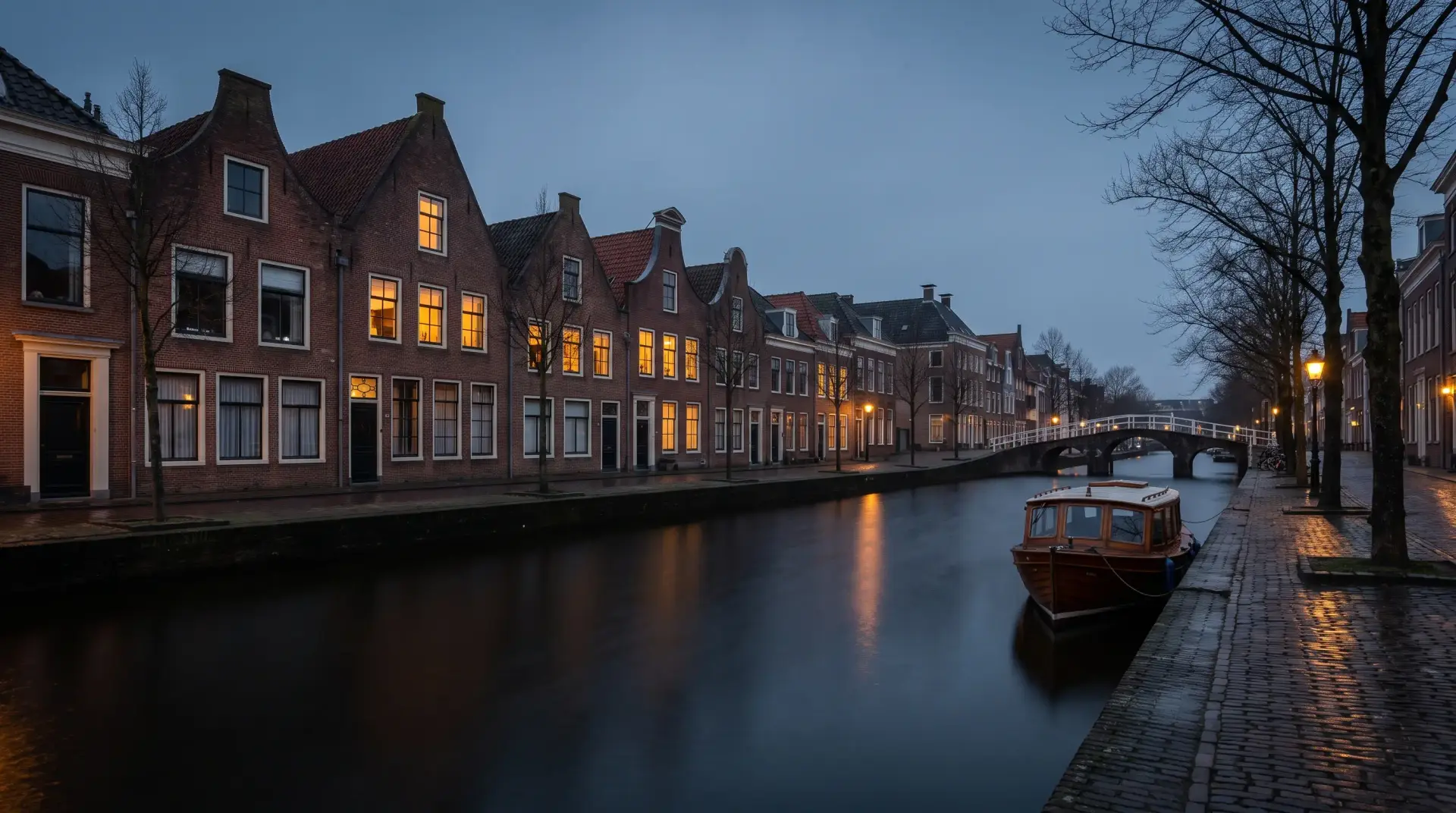 Nederlandse grachtenpanden met verlichte ramen in de avondschemering
