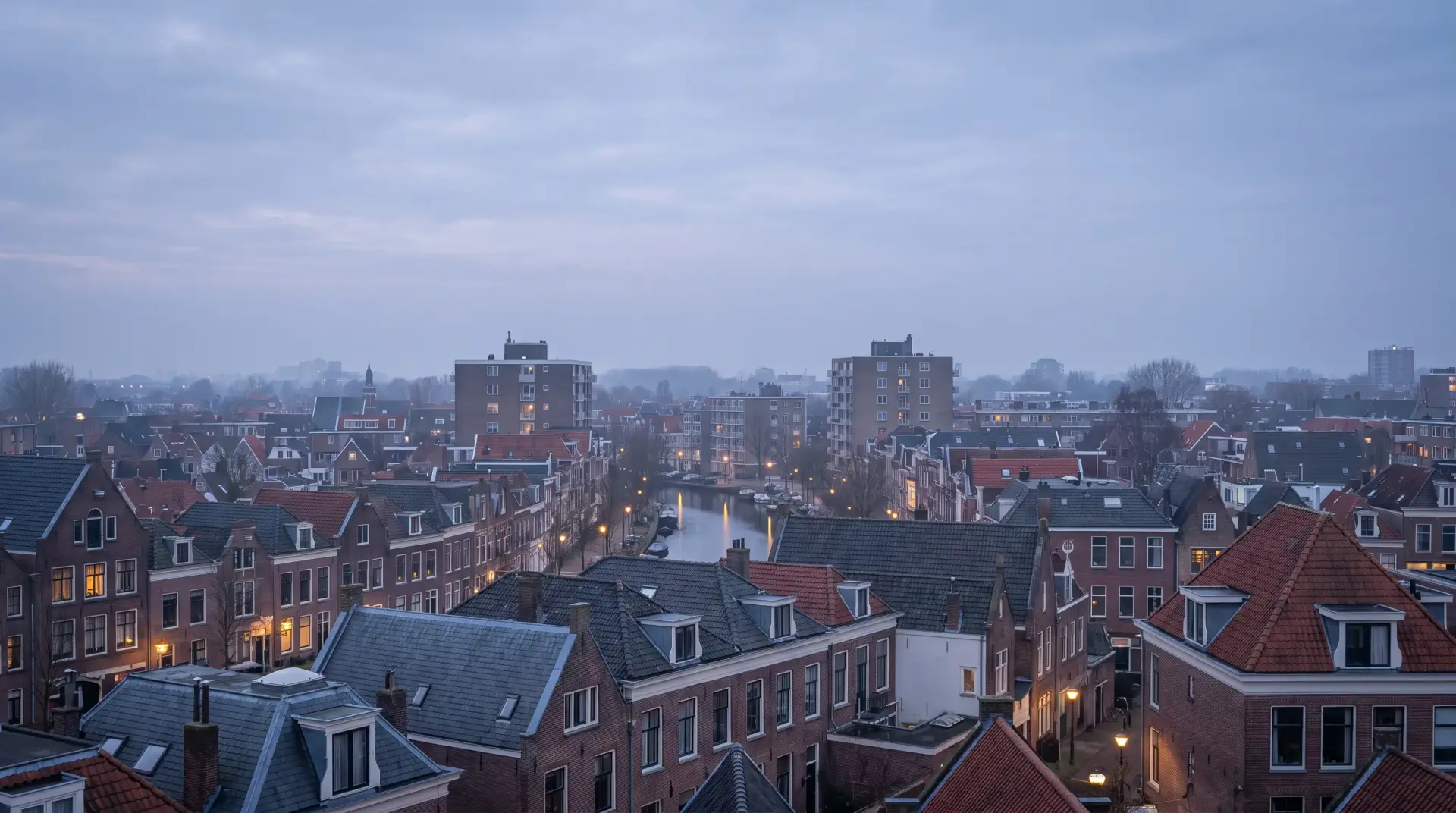 Uitzicht over de daken van een Nederlandse woonwijk in de avondschemering