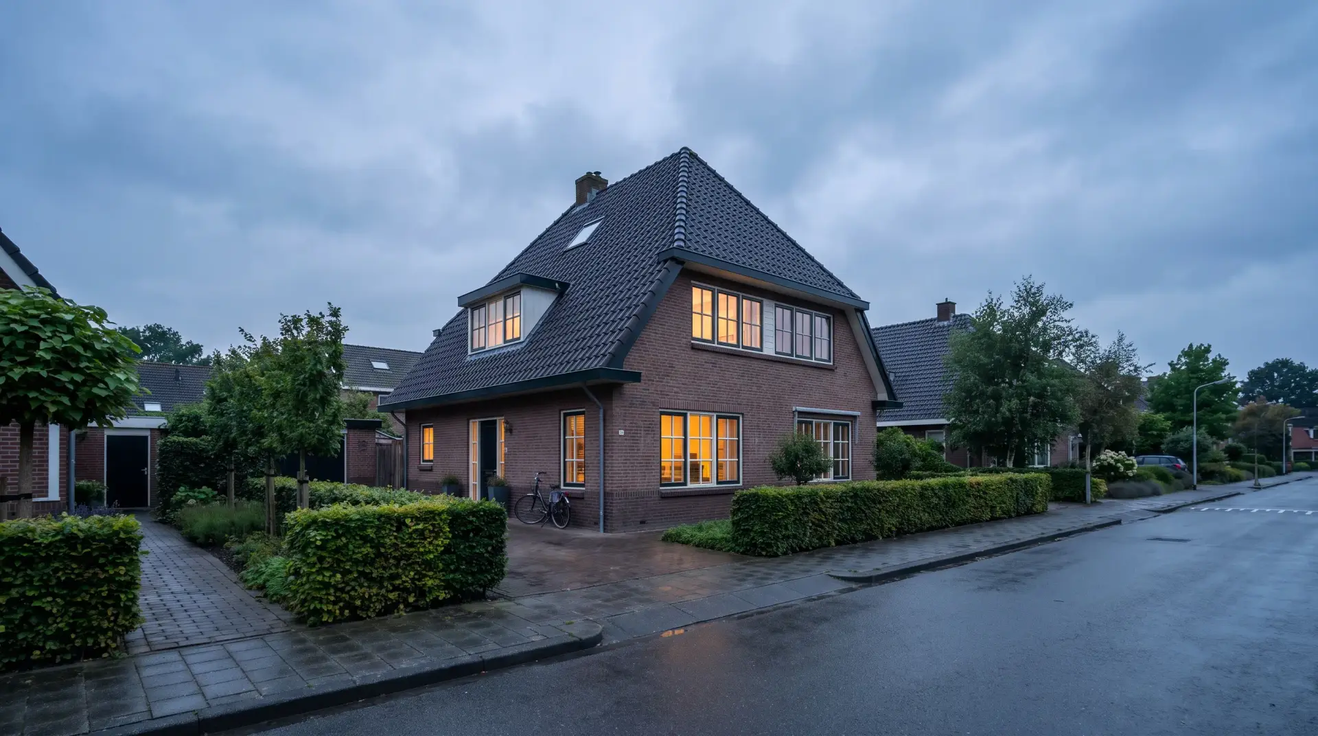 Vrijstaande Nederlandse woning met bakstenen gevel en voortuin in de avondschemering
